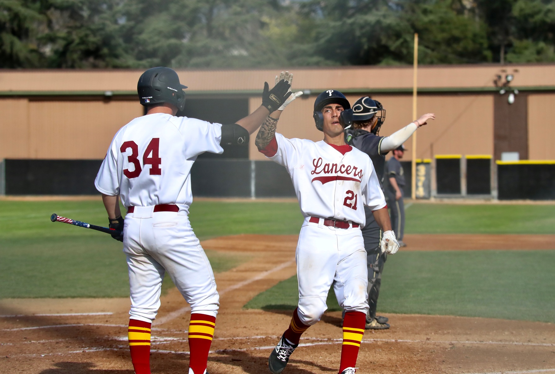 Gabe Arellano gets the high five from teammate Thomas Kolling in a recent baseball win, photo by Michael Watkins.